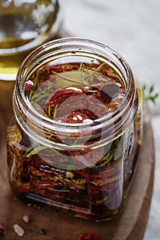 Dried tomatoes in a jar with fresh spices and olive oil