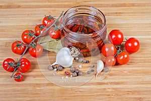 Dried tomatoes in olive oil in glass jar and ingredients