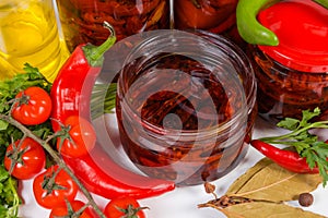 Dried tomatoes in olive oil in jar among ingredients closeup