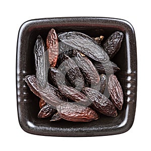 Dried tonka beans in black bowl isolated