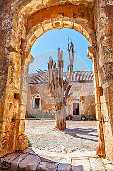 Dried tree behind the arch of old monastery