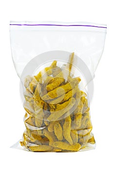 Dried turmeric rhizomes in plastic packet on a white