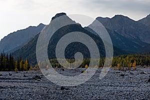 Dried up river bed in a rural countryside with the snowy mountains in the background. Majestic landscape with the rock road and