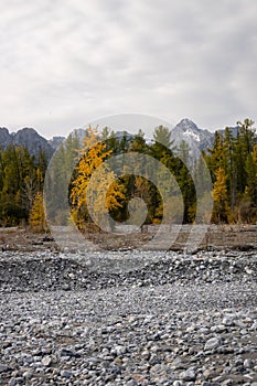 Dried up river bed in a rural countryside with the snowy mountains in the background. Majestic landscape with the rock road and