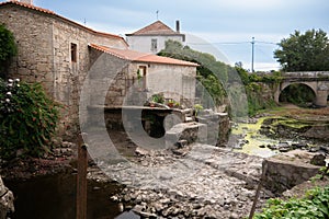Dried up River Este in Portugal during drought in summer. Old stone mill buildings on bank. photo