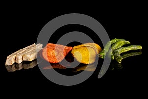 Dried vegetable chips isolated on black glass