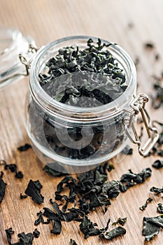 Dried wakame seaweed in jar on wooden table