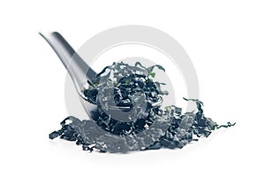 Dried wakame seaweed in spoon isolated on white background