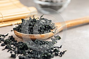 Dried wakame seaweed in spoon on kitchen table