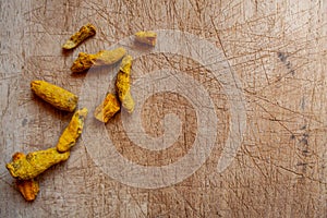 Dried whole turmeric on wooden cutting board background