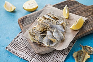 Dried yellow minke whales on blue background. Beer snack, dried seafood. Industrial catch, template