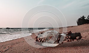 Drifted Glass bottle covered with sea shells on beach