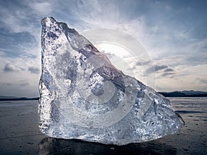 Drifting piece of iceberg and sun glaring on thick ice cover.