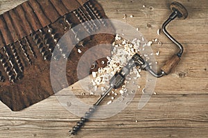 Drill brace with bits in leather tool roll on a wooden workbench