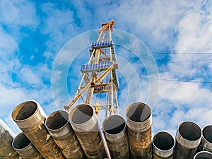 Drill and casing pipes on blurred image of oil rig.