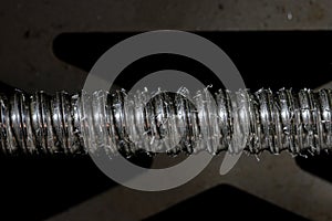 Drill from a milling machine in shiny metal shavings close up. Machining of metallic product for mechanical engineering