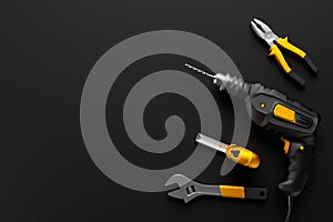 Drill, wrench and construction tools on the black background