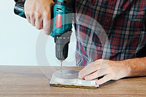 Drilling a Hard Disk Drive to Destroy Evidence Data close up.Cropped image of hand drilling on hard drive at table