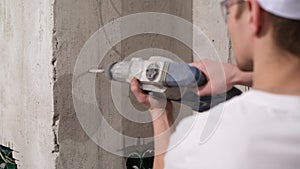 Drilling a hole in a concrete wall, close-up. The master works with a punch