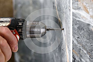 Drilling hole in tile with screwdriver.