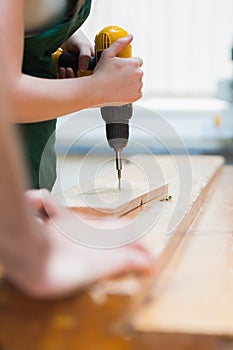Drilling a hole in a wooden board on the workbench