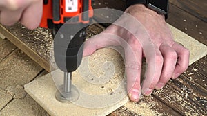 Drilling holes with a hand-held electric mini drill driver in a wood panel