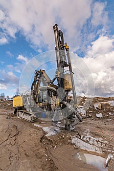 Drilling machine in a construction site surrounded by rock and mud