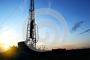 Drilling rig drills a well for the extraction of drinking water at sunset under a beautiful sky for drinking people