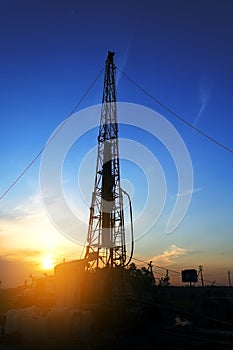 Drilling rig drills a well for the extraction of drinking water at sunset under a beautiful sky for drinking people