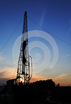 Drilling rig drills a well for the extraction of drinking water at sunset under a beautiful sky for drinking people