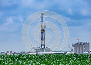 Drilling Rig and oil tanks with green cornfield in the foreground In South Texas Eagle Ford Shale