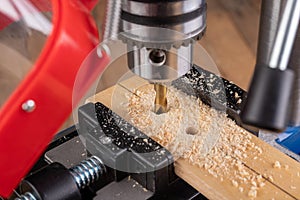 Drilling in wood with professional tools. Work on a bench drill