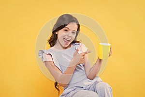 Drink it baby. Happy child point finger at cup yellow background. Little kid enjoy hot drink. Milk tea. Hot cacao or