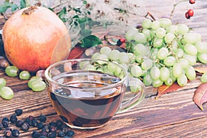 Drink From Dried Hawthorn Berries, A Bunch Of White Grapes And A Pomegranate On The Table Closeup