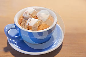 Drink Hot Chocolate topped by Milk Latte Foam with marshmallow in blue ceramic porcelain cup on wooden table background. Relaxed