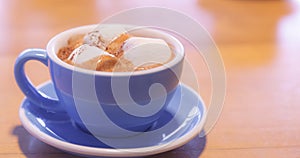 Drink Hot Chocolate topped by Milk Latte Foam with marshmallow in blue ceramic porcelain cup on wooden table background. Relaxed