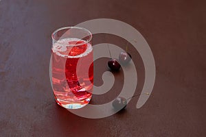 Drink with iced cherries, sweet cherries on a dark background. Fresh plum cocktail. Fresh summer cocktail with cherries and ice