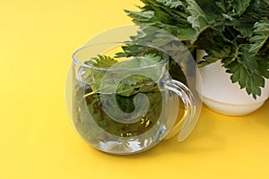 A drink made from nettle leaves stands on a yellow background.