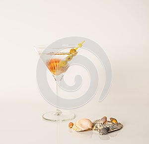 Drink in martini glass, martini drink with green olives, seashells