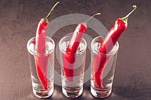 Drink set with shots of vodka and red pepper/Drink set with shots of vodka and red pepper on a dark stone background. Selective