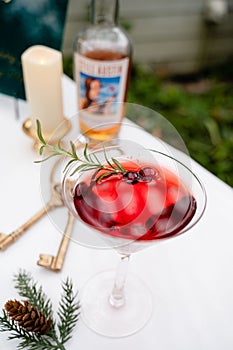 a drink sitting in a glass with a bottle and rosemary sprig