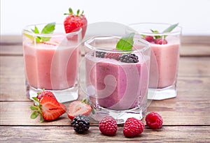 Drink smoothies four summer strawberry, blackberry, kiwi, raspberry on wooden table.