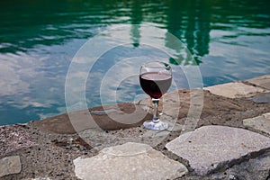 Drink in tall glass in poolside. Refreshment on summer day. Purple juice cocktail or vine.