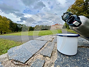 Drink tea on a hike against the background of the castle Duchcov, hands holding a thermos with a mug