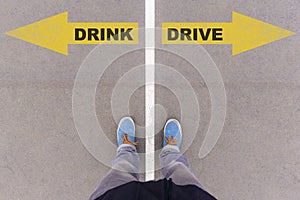 Drink vs drive text arrows on asphalt ground, feet and shoes on