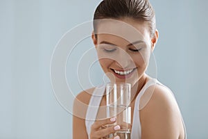 Drink water. Smiling woman holding fresh pure water in glass