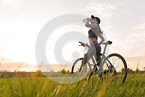 Drink water during workouts. sports. woman on bike sunset