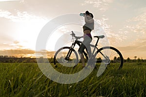 Drink water during workouts. sports. woman on bike sunset