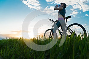 Drink water during workouts. sports. woman on bike sunset