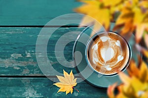 Drinking Coffee in Fall and Autumn Season. Hot Coffee Latte Cup on Blue Wooden Table. Top View. Focus on Latte Art in Heart Shape